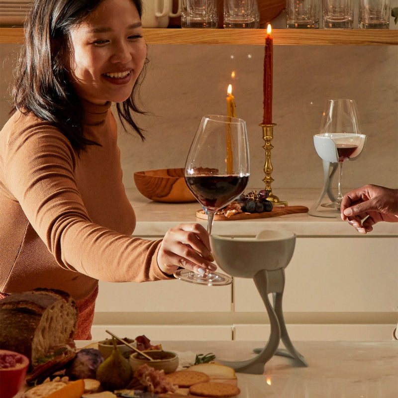 Woman lifting wine glass from a VoChill stemmed wine chillers at a dinner table with candles and food.