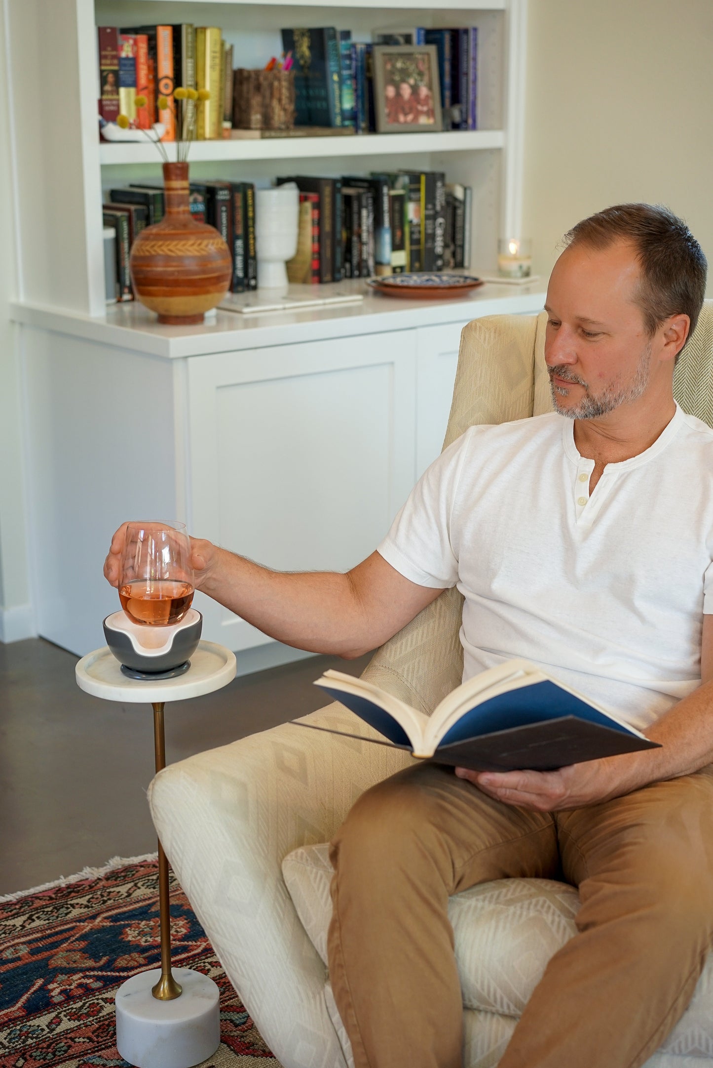 man reading book and drinking wine from a wine chiller. VoChill personal wine glass chiller.