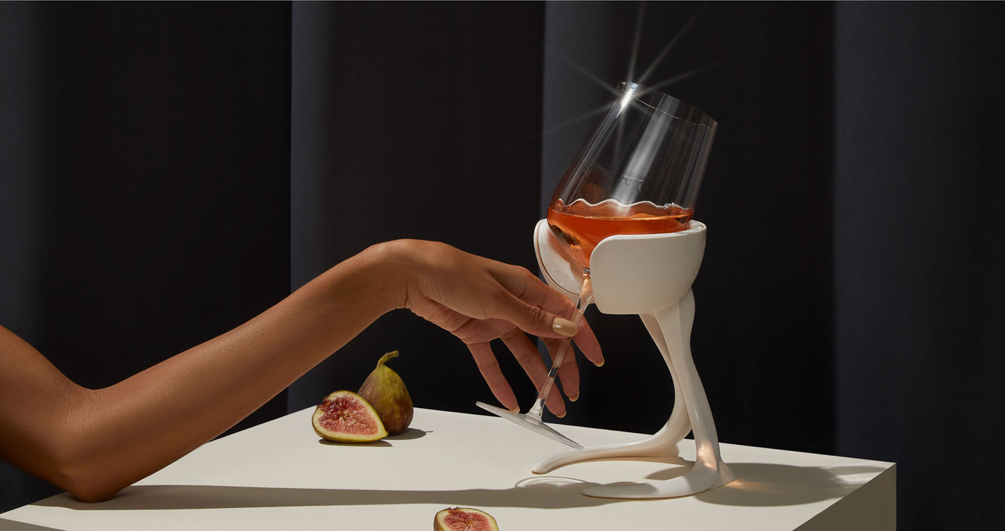 Studio shot of a hand elegantly lifting a stemmed glass of rosé wine from a stemmed wine chiller