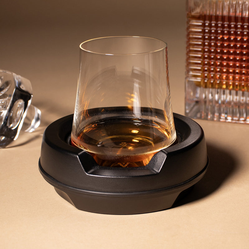 a close up photo of the vochill spirits chiller with whiskey in the glass setting an a tan paper surface