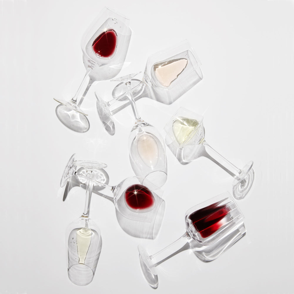 Arrangement of stemmed wine glasses laying on their side with wine in them