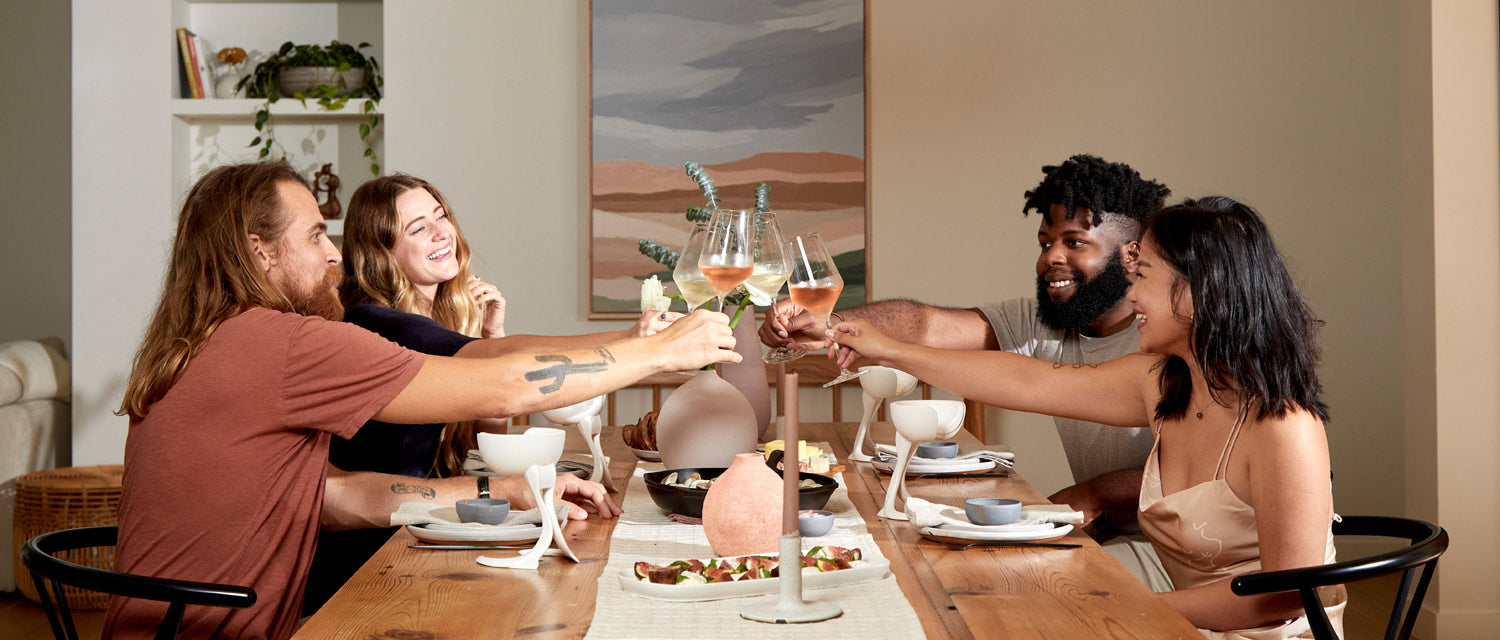 Group of friends sitting around a dining table giving cheers with their stemmed wine glasses and their stemmed VoChills