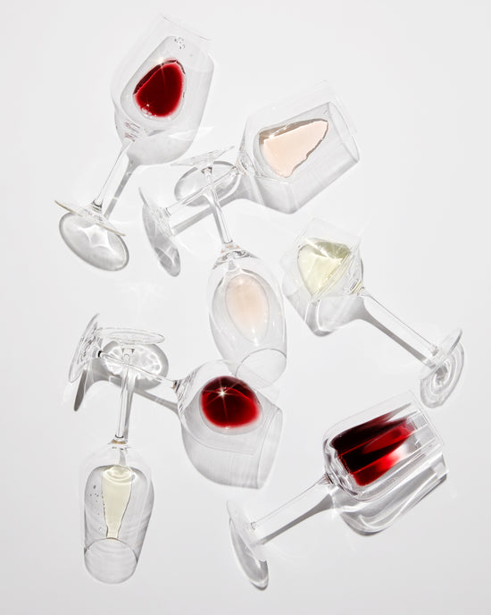 Stemmed wine glasses lay on their side with small amounts of red, white and rosé wines inside them. These glasses all fit with the VoChill Stemmed Wine Glass Chiller.