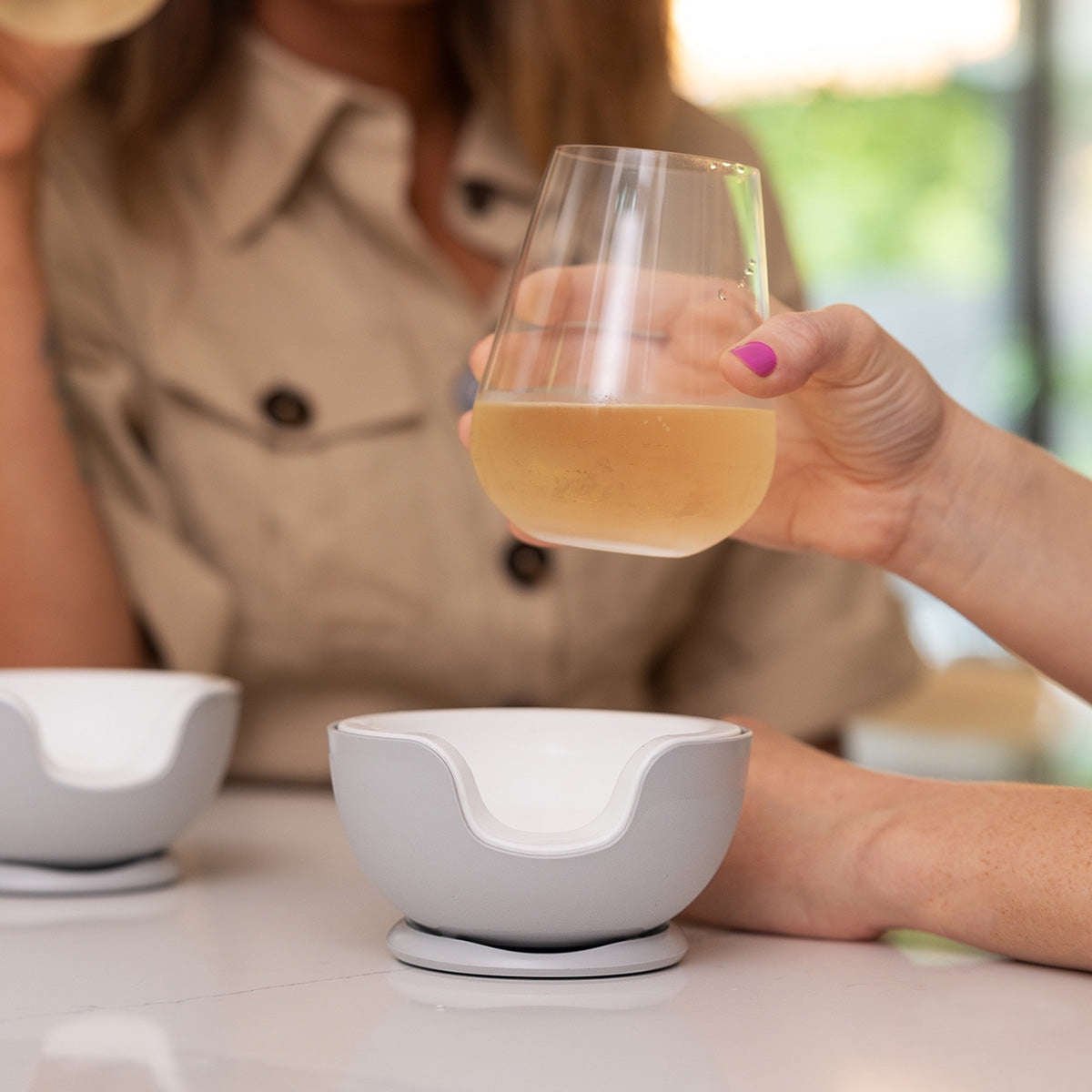 Hand placing a stemless wine glass into the VoChill wine chiller