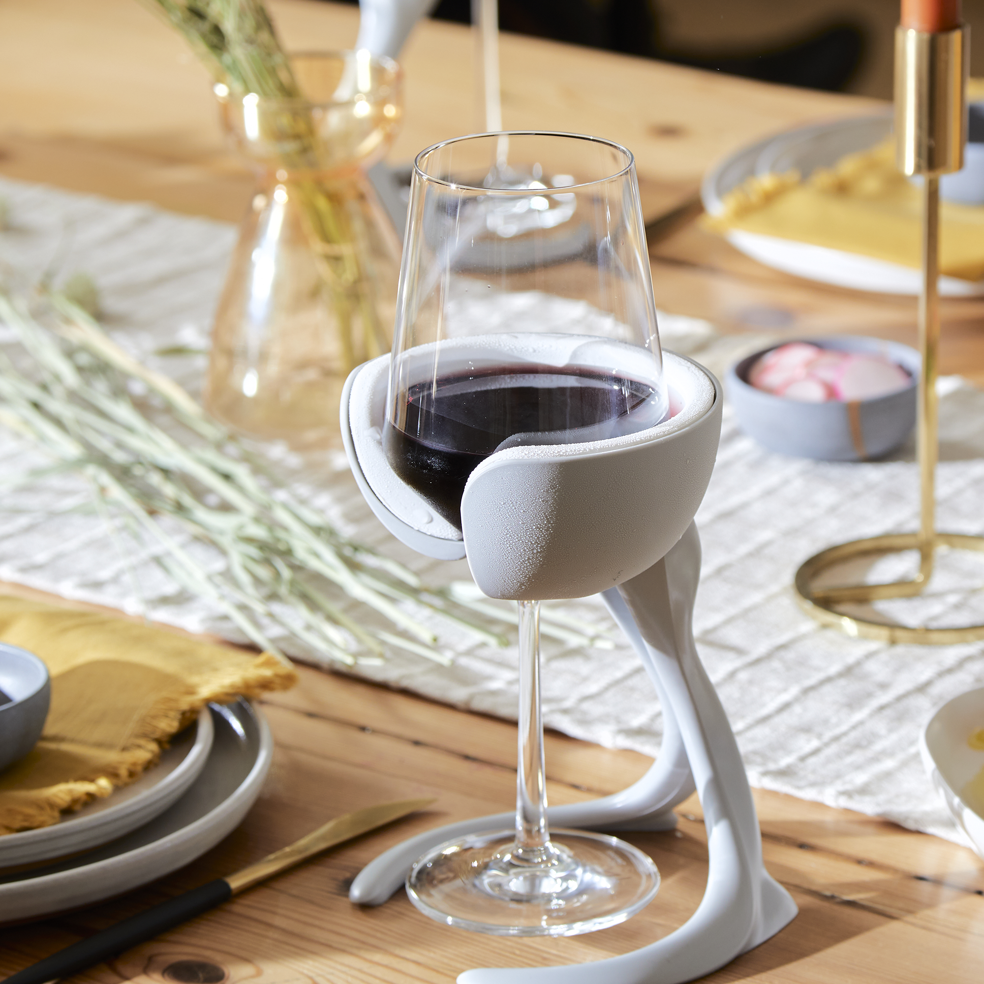 VoChill stemmed wine chiller holding a chilled glass of red wine on a beautiful dining table scape.
